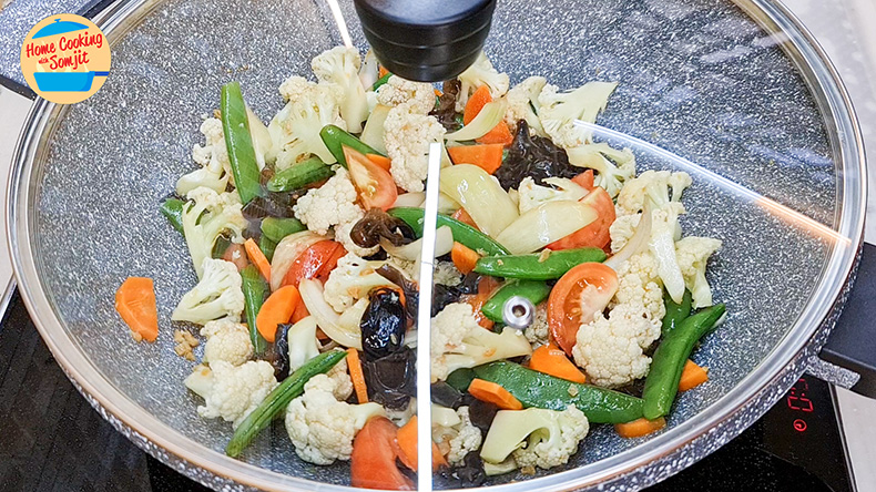 let them simmer Mixed vegetables simmering in a non-stick pan enclosed with a glass lid.