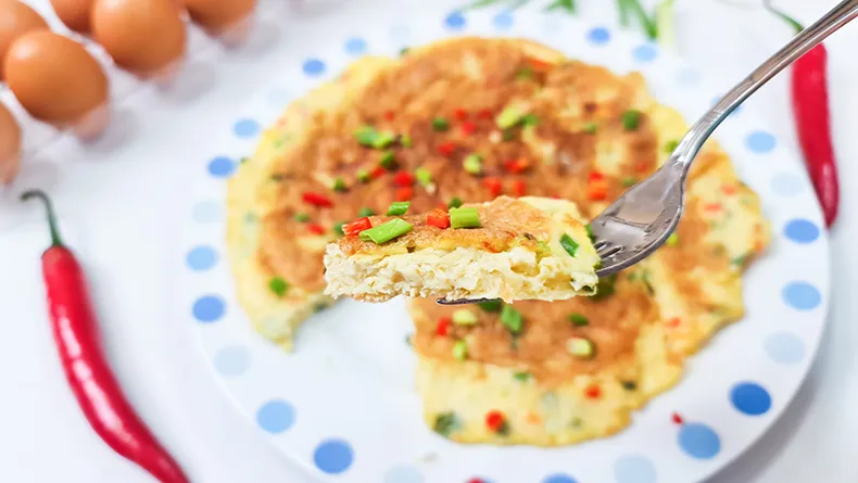 lets eat A fork holding up a piece of Fluffy Omelette.