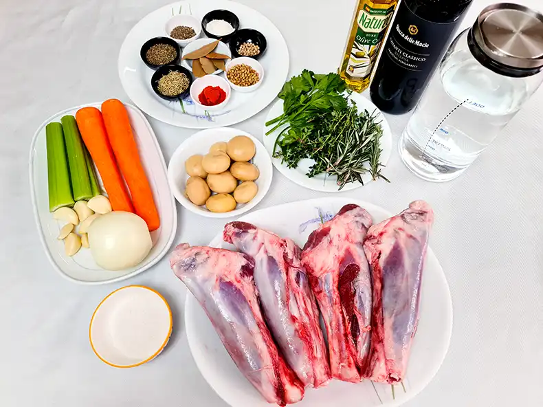 ingredients All the ingredients needed: dried spices, olive oil, red wine, water, fresh parsley, fresh thyme, fresh rosemary, lamb shanks, button mushrooms, carrots, celery, garlic, onion, salt and sugar.