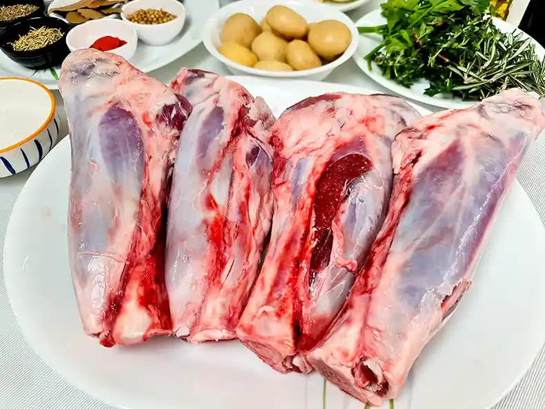 raw shanks Four raw lamb shanks on a plate, thawed and ready for marination.
