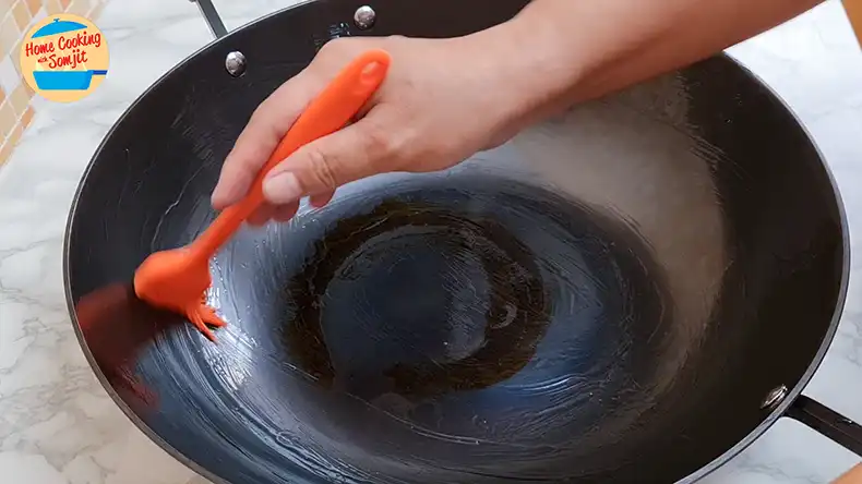 layer of oil for storage Silicone brush spreading cooking oil evenly inside an cast iron wok.