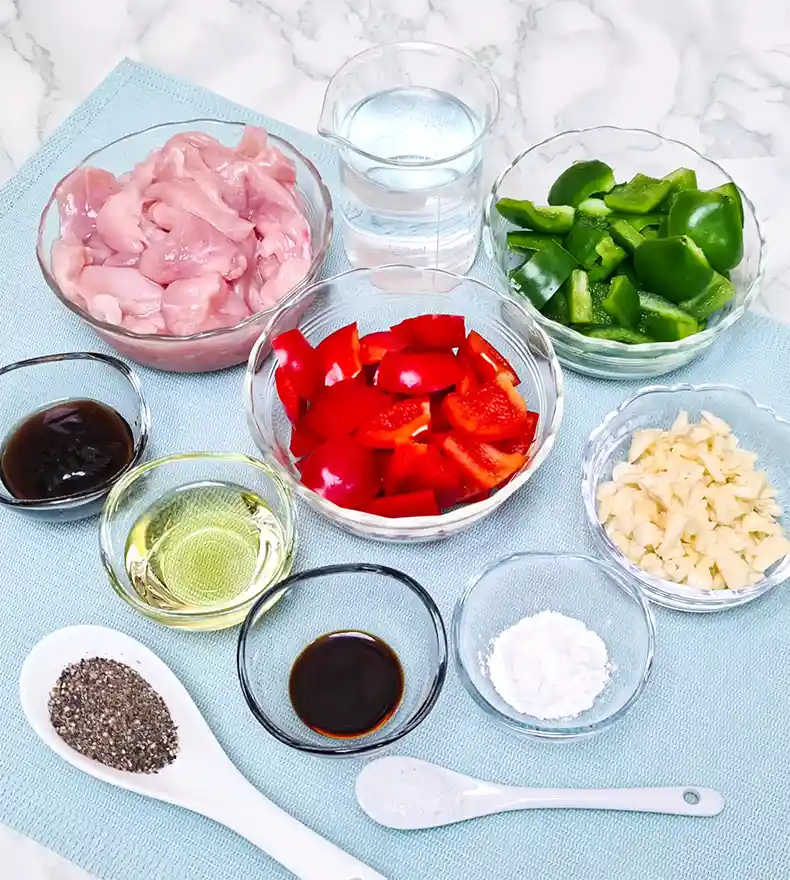 ingredients All the ingredients needed: sliced chicken, salt, tapioca flour, water, cooking oil, minced garlic, oyster sauce, light soy sauce, red and green capsicums, and coarse black pepper.