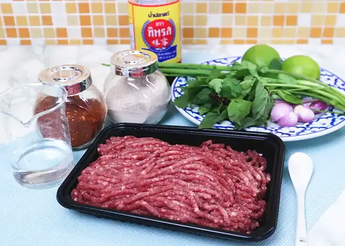 ingredients All the ingredients needed: minced beef, salt, water, cilantro, spring onions, sweet basil leaves, shallots, lime, fish sauce, ground chilli and roasted ground rice.
