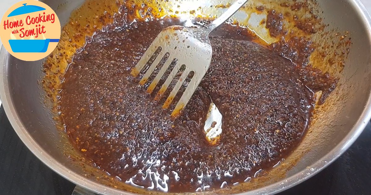 frying blended ingredients in oil Thick dark red viscous chilli jam being stirred in a pan.