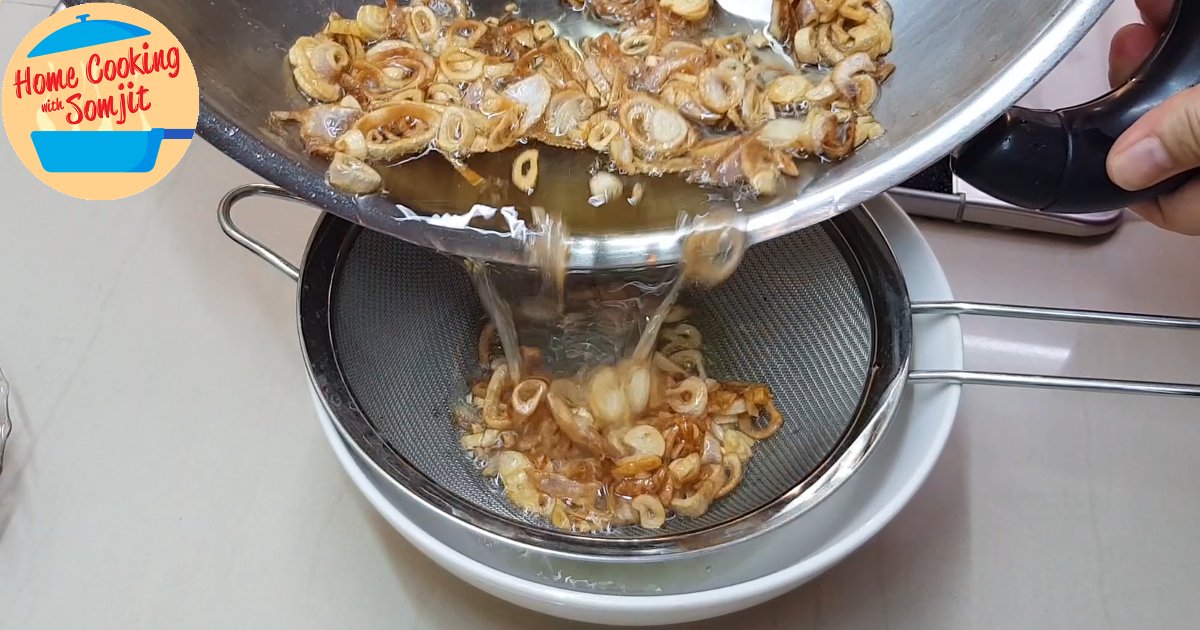 straining shallots Fried shallots & shallot oil being poured through a strainer over a bowl.